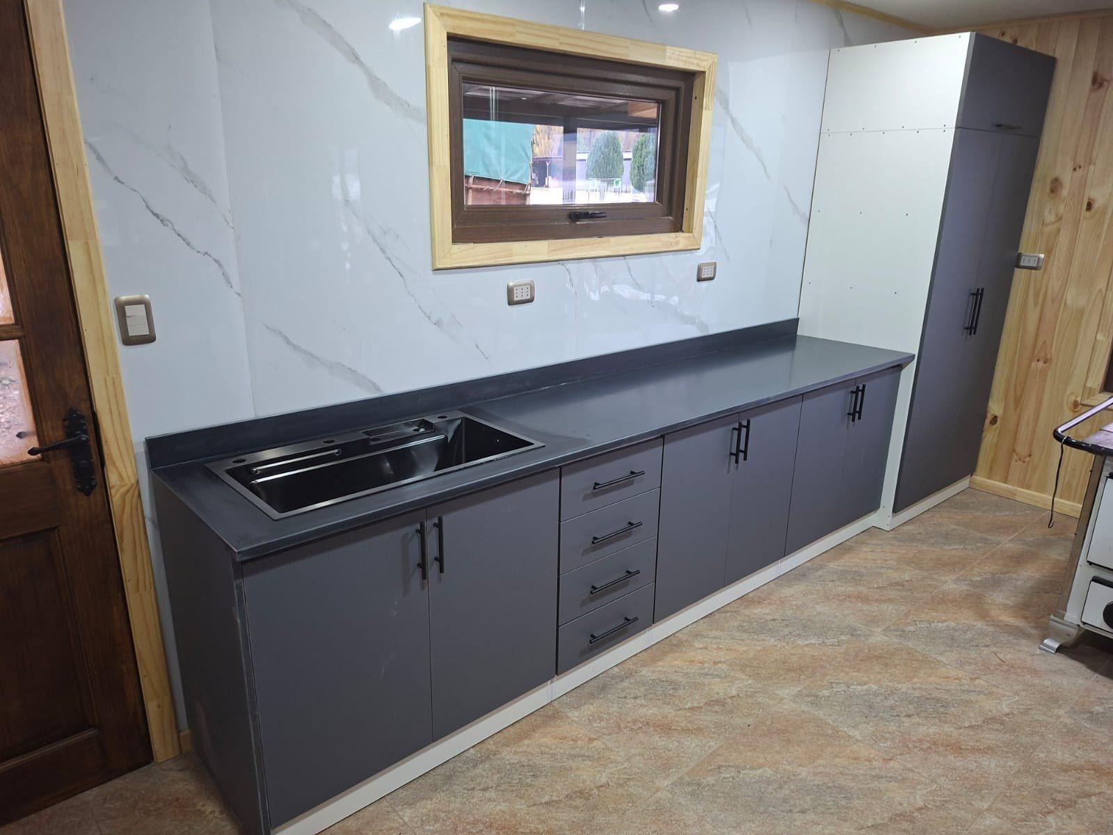 Cocina a medida en melamina gris con cubierta negra y ventana con luz natural